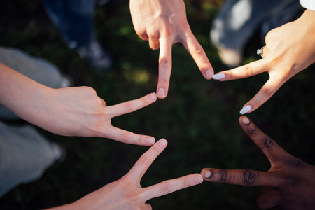 Hands of different skin tones create a star shape with fingers on grass, symbolizing unity and...