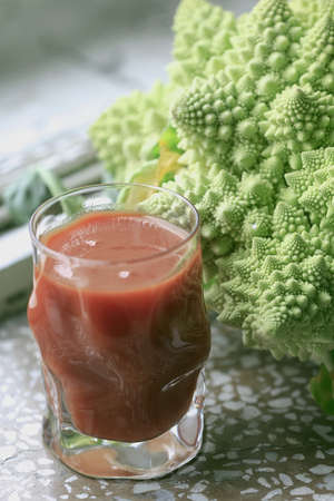 Tomato juice in glass and cabbage green fresh romanescoの写真素材
