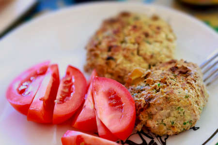 Cutlets and red tomato slices on plateの写真素材