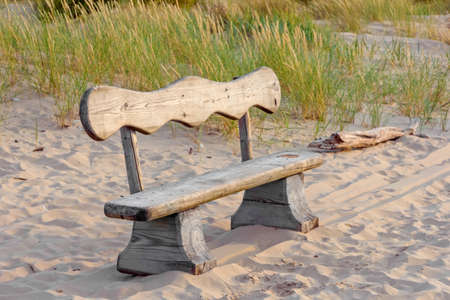 Wooden bench on summer sandy beach in sunset lightの写真素材