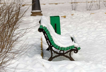 Wood green snowy bench in winter parkの写真素材