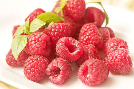 Appetite red fresh raspberries on white plate