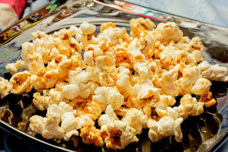 Nice golden popcorn on black plate for eatingの写真素材