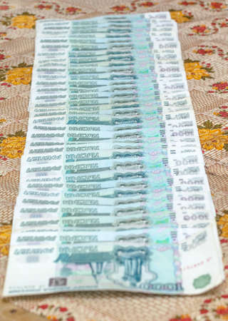Russian thousands of rubles banknotes on colorful tablecloth at day