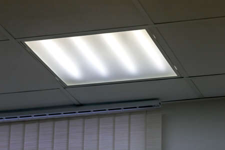 Fluorescent light on ceiling in grey officeの写真素材