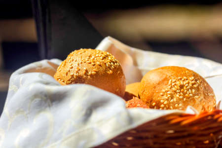 White rolls with sesame seeds in basket with fabric napkinの写真素材