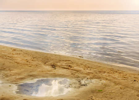 Evening relax by quiet sea at summer day, puddle of sand on shoreの写真素材