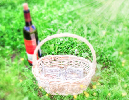 Picnic on green summer grass, glasses in basket and wineの写真素材