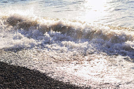 Sea surf on pebble beach at sunny morningの写真素材