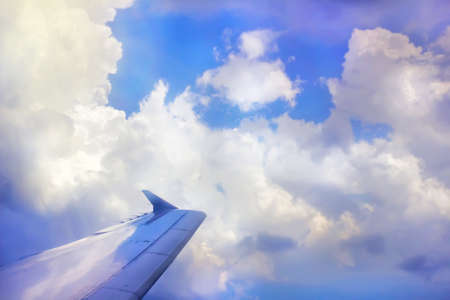 Wing of plane in clouds at sunny weatherの写真素材