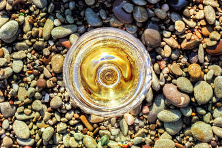 Glass of white wine on sea pebblesの写真素材