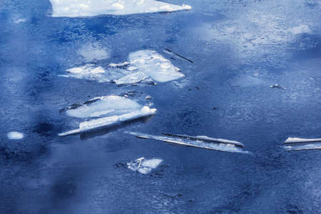 Ice in blue deep water at winter cloudy weather