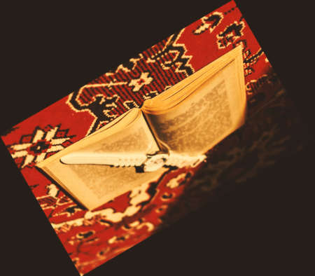 Open book with clock upside down on red carpetの写真素材