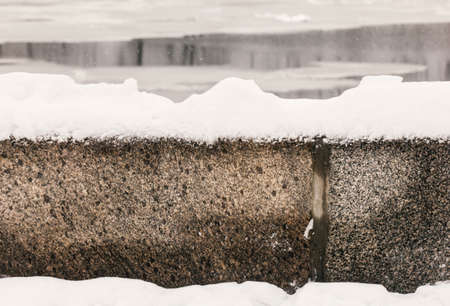 White clear snow on granite fence at cloudy winter dayの写真素材