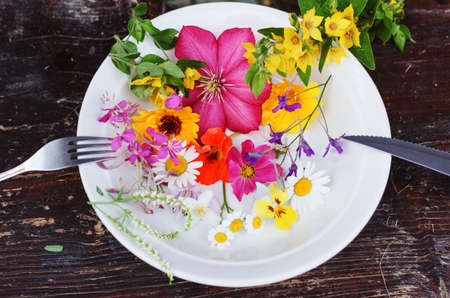 Multicolour flowers in plate fork and knifeの写真素材