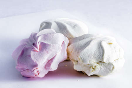 Three marshmallows, pink and white, on gray background