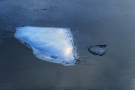 Real large white ice floe in dark water winter cloudy day