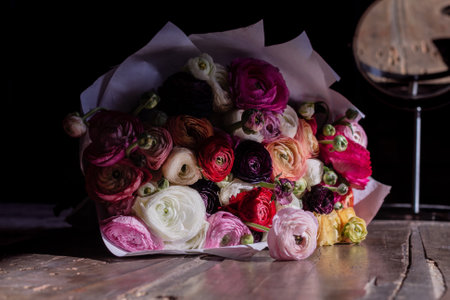Pretty bouquet of multicolored ranunculus on wooden table in partial shade for crewの写真素材