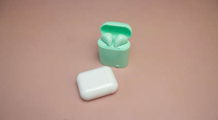 white wireless headphones, green wireless headphones on pink background
