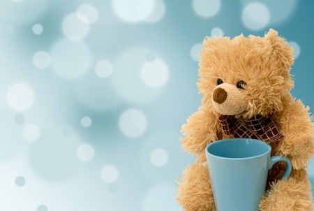 teddy bear with a blue cup on a blue backgroundの写真素材