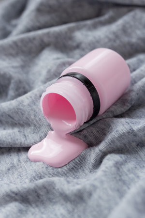 One pink tube of paint open, small bottle of colors spilled, artist material for work, pastel palette, creative splash of colorの写真素材