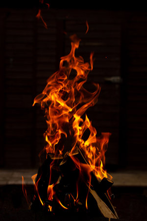 Fire flames on vertical photo, wild hot bonfire, heat energy heap close up, red and yellow on black backgroundの写真素材