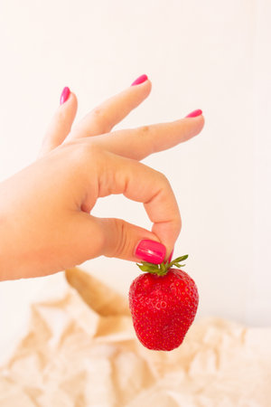 One red strawberry in woman hand, season of summer berries, vegetarian diet, natural yummy food for healthの写真素材