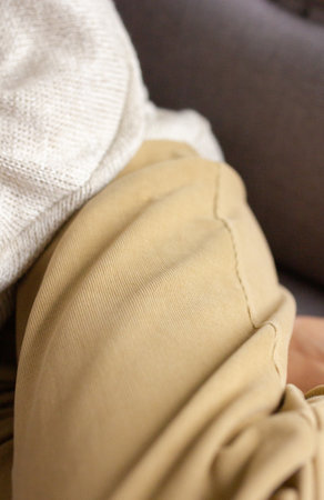 Mustard pants with gathers on woman legs close up, apparel model in trendy trousers, fabric texture...