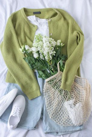 Eco fashion blogger content with clothes flat lay and white flowers