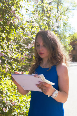 Female artist painting in botanical garden. Young woman drawing watercolor sketch in front of...