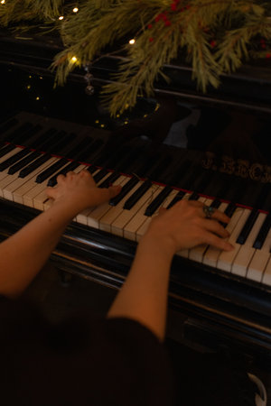 Female musician hand touching white black keys. Woman plays the piano on festive background. Girl in...