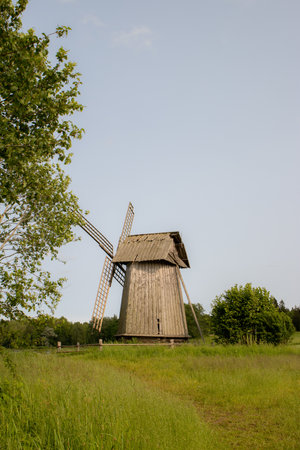 Traditional wooden windmill with large blades in scenic village field. Symbol of past craftsmanship...
