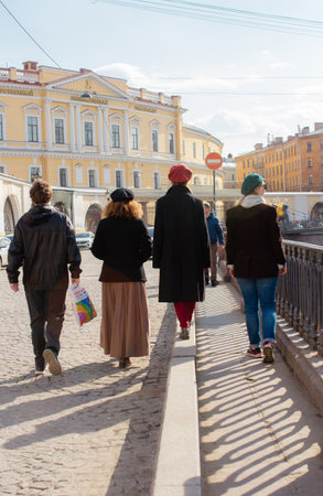Women exploring the cultural heritage of Saint Petersburg, Russia, back of four people walking along a picturesque street with historical houses, European-style architecture, and urban atmosphereの写真素材