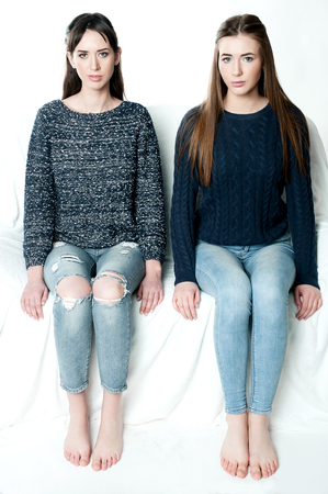 Young and beautiful sisters in friendship, sharing joy, trust, love, happiness and support, hugs, laughs and smiles wearing jeansの写真素材