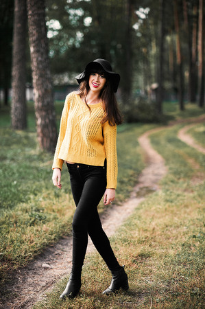 Portrait of a brunnete happy and smiling girl in a black hat and yellow sweaterの写真素材
