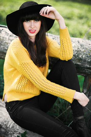 Portrait of a brunnete happy and smiling girl in a black hat and yellow sweaterの写真素材