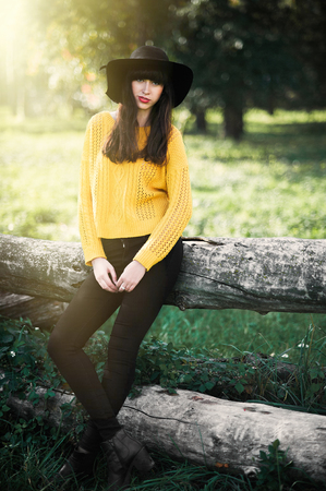 Portrait of a brunnete happy and smiling girl in a black hat and yellow sweaterの写真素材