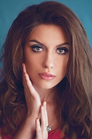a studio portrait of a young woman with long and wavy hair and blue eyes. her make-up is very colorful; it is inspired by the '60s styleの写真素材