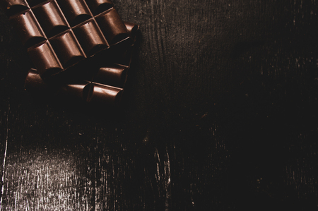 Cup of coffee with grains and chocolate on wooden table on dark backgroundの写真素材