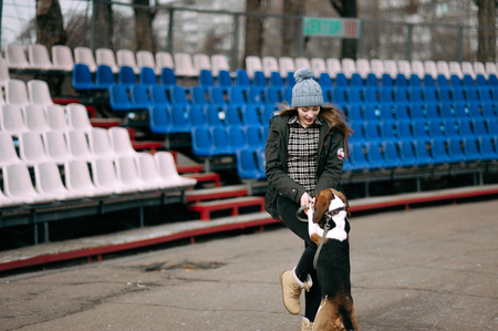 Young hipster girl with her pet estonian hound dog playing and having fun outdoor in the park.の写真素材