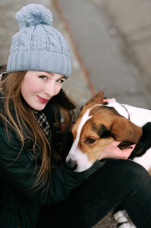 Young hipster girl with her pet estonian hound dog playing and having fun outdoor in the park.