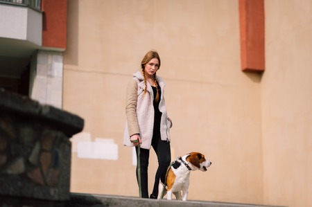 Young hipster girl with her pet estonian hound dog playing and having fun outdoor in the park.の写真素材