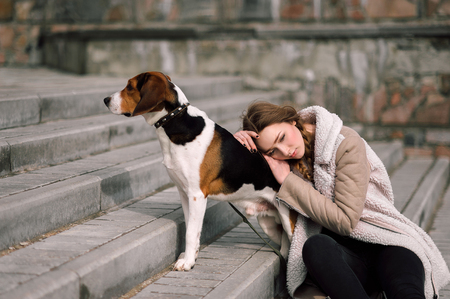 Young hipster girl with her pet estonian hound dog playing and having fun outdoor in the park.の写真素材