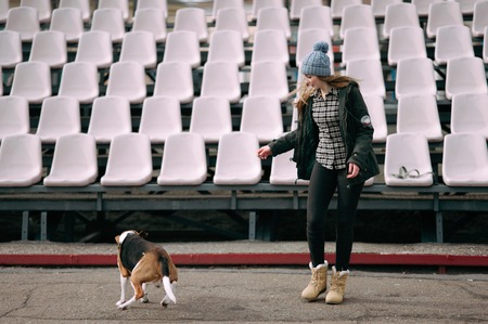 Young hipster girl with her pet estonian hound dog playing and having fun outdoor in the park.の写真素材