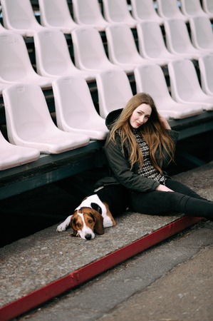 Young hipster girl with her pet estonian hound dog playing and having fun outdoor in the park.の写真素材