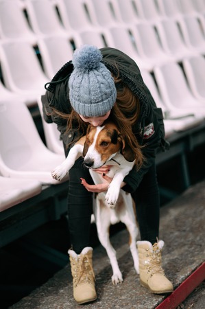 Young hipster girl with her pet estonian hound dog playing and having fun outdoor in the park.の写真素材