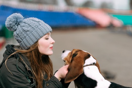 Young hipster girl with her pet estonian hound dog playing and having fun outdoor in the park.の写真素材