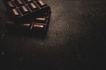 Cup of coffee with grains and chocolate on wooden table on dark backgroundの写真素材