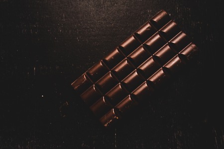 Cup of coffee with grains and chocolate on wooden table on dark backgroundの写真素材