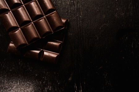 Cup of coffee with grains and chocolate on wooden table on dark backgroundの写真素材